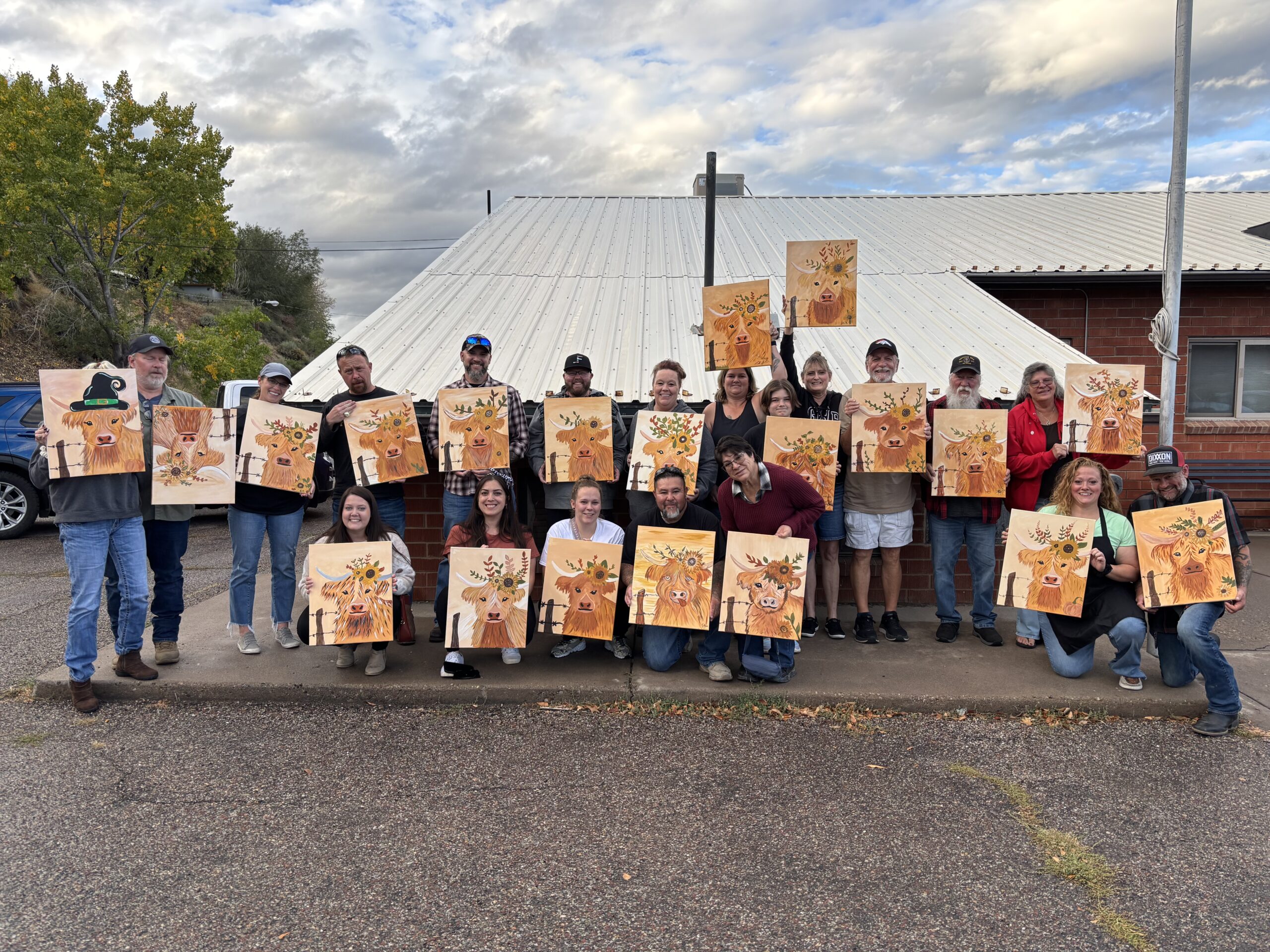 People smiling and showing their painting after a paint and sip event 